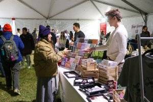 Denzel Decker of Down to Earth Living making a sale to a customer at the Jingle and Mingle Holiday Market.